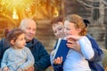 Beautiful Happy Old couple and granddaughters reading a book together in the nature at sunset. Royalty Free Stock Photo