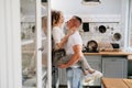 Pair of lovers kissing and hugging in kitchen next to the refrigerator