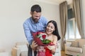 Beautiful, happy, positive couple embracing, holding bouquet of red roses, 14 February happy Valentines day