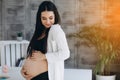 Beautiful happy pregnant african woman hugging her tummy, sitting on sport mat, enjoying her pregnancy, free space Royalty Free Stock Photo