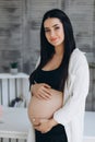 Beautiful happy pregnant african woman hugging her tummy, sitting on sport mat, enjoying her pregnancy, free space Royalty Free Stock Photo