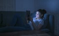 beautiful happy and relaxed latin woman 30s lying on home couch late night using digital device laptop tablet pad watching Royalty Free Stock Photo