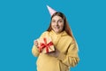 Beautiful happy 30s woman with gift box posing isolated on blue background, studio portrait. Birthday celebrating Royalty Free Stock Photo