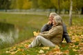 Beautiful happy senior couple relaxing in park with autumn leaves Royalty Free Stock Photo