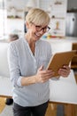 Beautiful happy senior woman using tablet computer at home Royalty Free Stock Photo