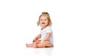 Beautiful, happy, smiling child. Little baby girl, toddler sitting on floor with joy and fun against white studio Royalty Free Stock Photo