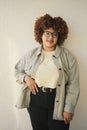 Beautiful happy smiling curvy plus size African black woman afro hair posing beige t-shirt, jeans, stylish glasses on