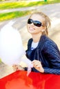 Beautiful happy smiling girl in sunglasses eating cotton candy at a table in the Park on a Sunny day Royalty Free Stock Photo