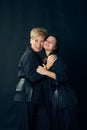 Beautiful happy smiling middle-aged woman, mother posing with young girl, daughter over dark studio background. Concept Royalty Free Stock Photo