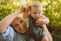 Beautiful happy smiling senior elderly woman holding on hands cute little baby boy sitting outdoor. Grandmother grandson Royalty Free Stock Photo