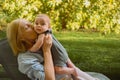 Beautiful happy smiling senior elderly woman holding on hands cute little baby boy sitting outdoor. Grandmother grandson