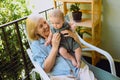 Beautiful happy smiling senior elderly woman holding on hands cute little baby boy sitting on outdoor rocking chair Royalty Free Stock Photo