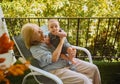 Beautiful happy smiling senior elderly woman holding on hands cute little baby boy sitting on outdoor rocking chair Royalty Free Stock Photo