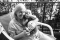 Beautiful happy smiling senior elderly woman holding on hands cute little baby boy sitting on outdoor rocking chair Royalty Free Stock Photo