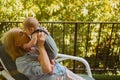 Beautiful happy smiling senior elderly woman holding on hands cute little baby boy sitting on outdoor rocking chair Royalty Free Stock Photo