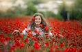 Beautiful happy smiling teen girl portrait with red flowers on head enjoying in poppies field nature background. Makeup Royalty Free Stock Photo