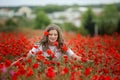 Beautiful happy smiling teen girl portrait with red flowers on head enjoying in poppies field nature background. Makeup Royalty Free Stock Photo