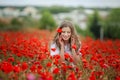 Beautiful happy smiling teen girl portrait with red flowers on head enjoying in poppies field nature background. Makeup Royalty Free Stock Photo