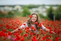 Beautiful happy smiling teen girl portrait with red flowers on head enjoying in poppies field nature background. Makeup Royalty Free Stock Photo