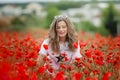 Beautiful happy smiling teen girl portrait with red flowers on head enjoying in poppies field nature background. Makeup Royalty Free Stock Photo