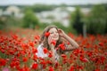 Beautiful happy smiling teen girl portrait with red flowers on head enjoying in poppies field nature background. Makeup Royalty Free Stock Photo