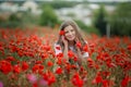 Beautiful happy smiling teen girl portrait with red flowers on head enjoying in poppies field nature background. Makeup Royalty Free Stock Photo