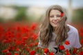 Beautiful happy smiling teen girl portrait with red flowers on head enjoying in poppies field nature background. Makeup Royalty Free Stock Photo