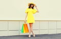 Beautiful happy smiling woman with shopping bags wearing yellow dress and summer straw hat in the city Royalty Free Stock Photo