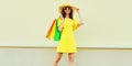 Beautiful happy smiling woman with shopping bags wearing yellow dress and summer straw hat in the city Royalty Free Stock Photo