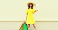 Beautiful happy smiling woman with shopping bags wearing yellow dress and summer straw hat in the city Royalty Free Stock Photo