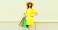 Beautiful happy smiling woman with shopping bags wearing yellow dress and summer straw hat in the city Royalty Free Stock Photo