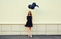 Beautiful happy smiling young woman full length with bunch of black and white balloons in summer dress on city street Royalty Free Stock Photo