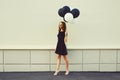 Beautiful happy smiling young woman full length with bunch of black and white balloons in summer dress on city street Royalty Free Stock Photo