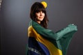 Beautiful happy smiling young woman holding Brazil flag wearing soccer top with flowers in her hairs Royalty Free Stock Photo