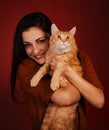 Beautiful happy smiling young woman holding on the hands and hugging with love her red maine coon kitten. Closeup portrait Royalty Free Stock Photo