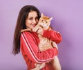 Beautiful happy smiling young woman holding on the hands and hugging with love her red maine coon kitten. Closeup portrait Royalty Free Stock Photo