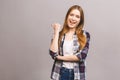 Beautiful happy smiling young woman pointing away and looking isolated over grey background. Free copyspace for product or text Royalty Free Stock Photo