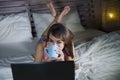 Beautiful and happy student woman enjoying on bed with laptop computer watching internet movie or having video chat call with frie