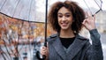 Beautiful happy successful lady curly african american woman girl with transparent umbrella stands in autumn city in Royalty Free Stock Photo