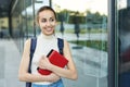 Beautiful happy woman with a backpack going to college. Young female university student with books in campus.