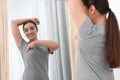 Beautiful happy woman doing breast self-examination near mirror indoors Royalty Free Stock Photo