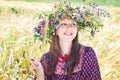 Beautiful happy woman in flower wreath in summer