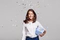 Beautiful happy woman with gift box at celebration party with confetti falling everywhere on her. Royalty Free Stock Photo