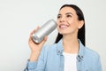 Beautiful happy woman holding beverage can on light grey background, closeup Royalty Free Stock Photo