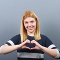 Beautiful happy woman holding heart in hands against gray background Royalty Free Stock Photo