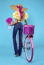 Beautiful happy woman in jeans and big hat with colorful bike decorated with flowers. Spring fashion concept