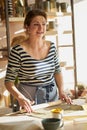 Beautiful happy  woman making ceramic ware in workplace, smiling in sun light. Concept for woman in freelance, business, hobby Royalty Free Stock Photo