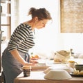 Beautiful happy woman making ceramic ware in workplace in sun light. Concept for woman in freelance, business, hobby Royalty Free Stock Photo