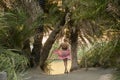 Beautiful happy woman is posing by branches of palm trees at tropical coast in Preveli beach on Crete island Royalty Free Stock Photo