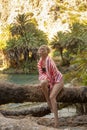 Beautiful happy woman is posing by branches of palm trees at tropical coast in Preveli beach on Crete island Royalty Free Stock Photo